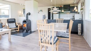 Une cuisine moderne dotée d’un îlot central, de chaises en bois, d’une table à manger et d’un poêle à bois.