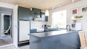 Une cuisine moderne dotée d’un îlot central, d’appareils électroménagers intégrés et de luminaires suspendus.
