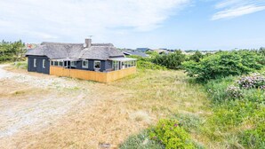 Une maison située sur la côte, avec un toit de chaume, une terrasse en bois et une vue sur la mer.