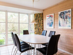 A modern dining area with a round table, black chairs, and a hanging pendant light. - 4 Star Holiday Home in Norre Nebel (Norre Nebel)