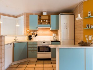 A compact kitchen with teal cabinets, a white refrigerator, and a coffee maker. - 4 Star Holiday Home in Norre Nebel (Norre Nebel)