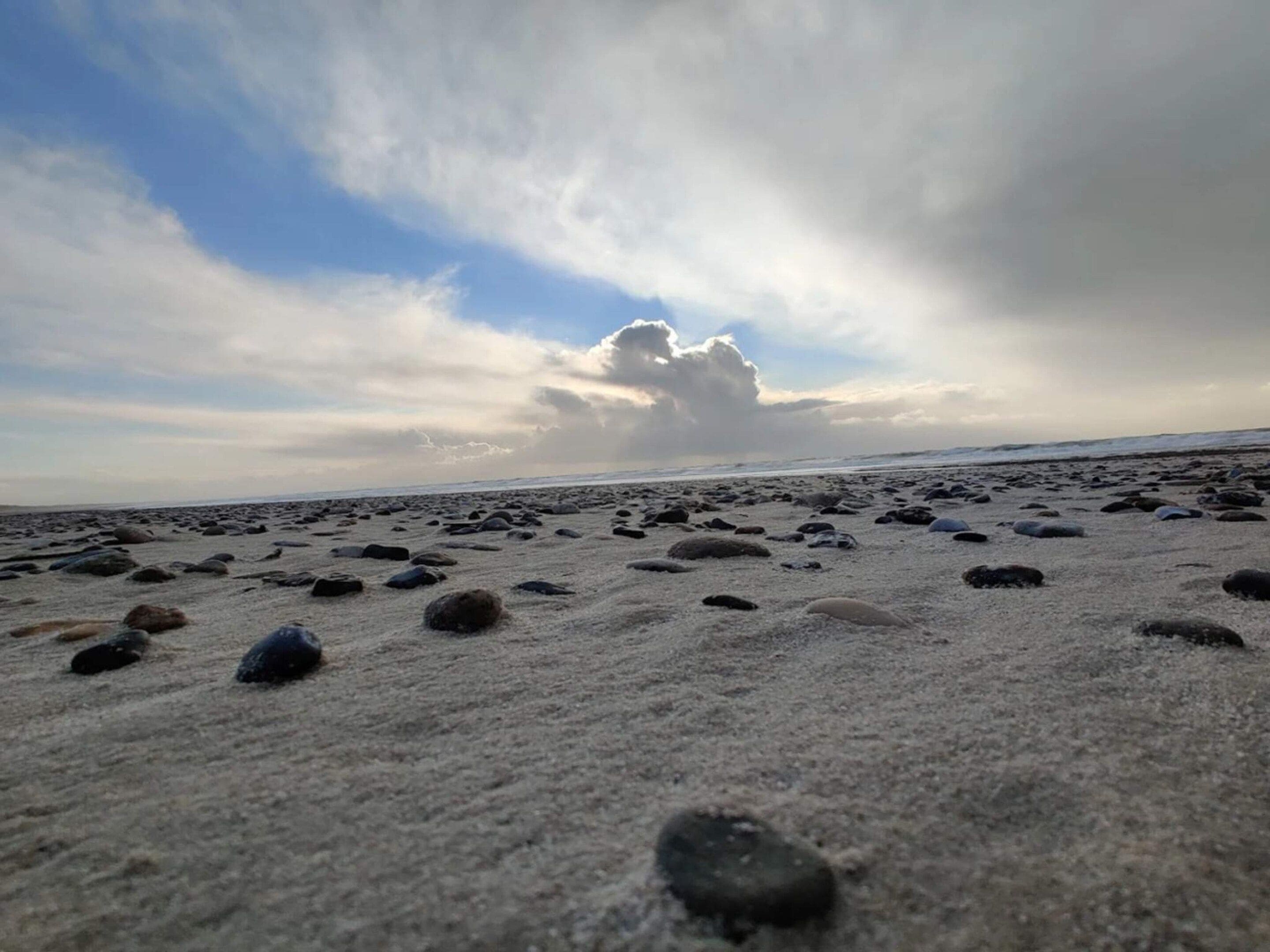 A beach with scattered rocks and a cloudy sky.