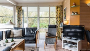 Un salon moderne avec un canapé, un fauteuil, un téléviseur et une table basse.