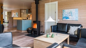 Un salon moderne avec une cheminée, un canapé, une table basse et une cuisine en arrière-plan.