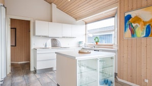 A modern kitchen with white cabinetry, a glass-fronted display case, and a wooden ceiling.