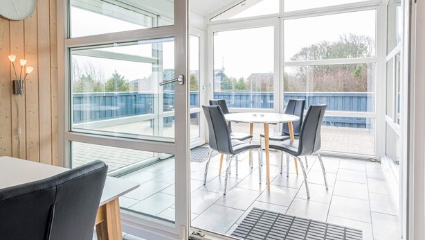 A modern room with a glass door leading to an outdoor patio with a table and chairs.