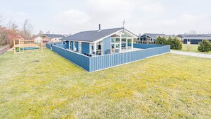 A modern house with a large deck, a play area, and a spacious backyard.