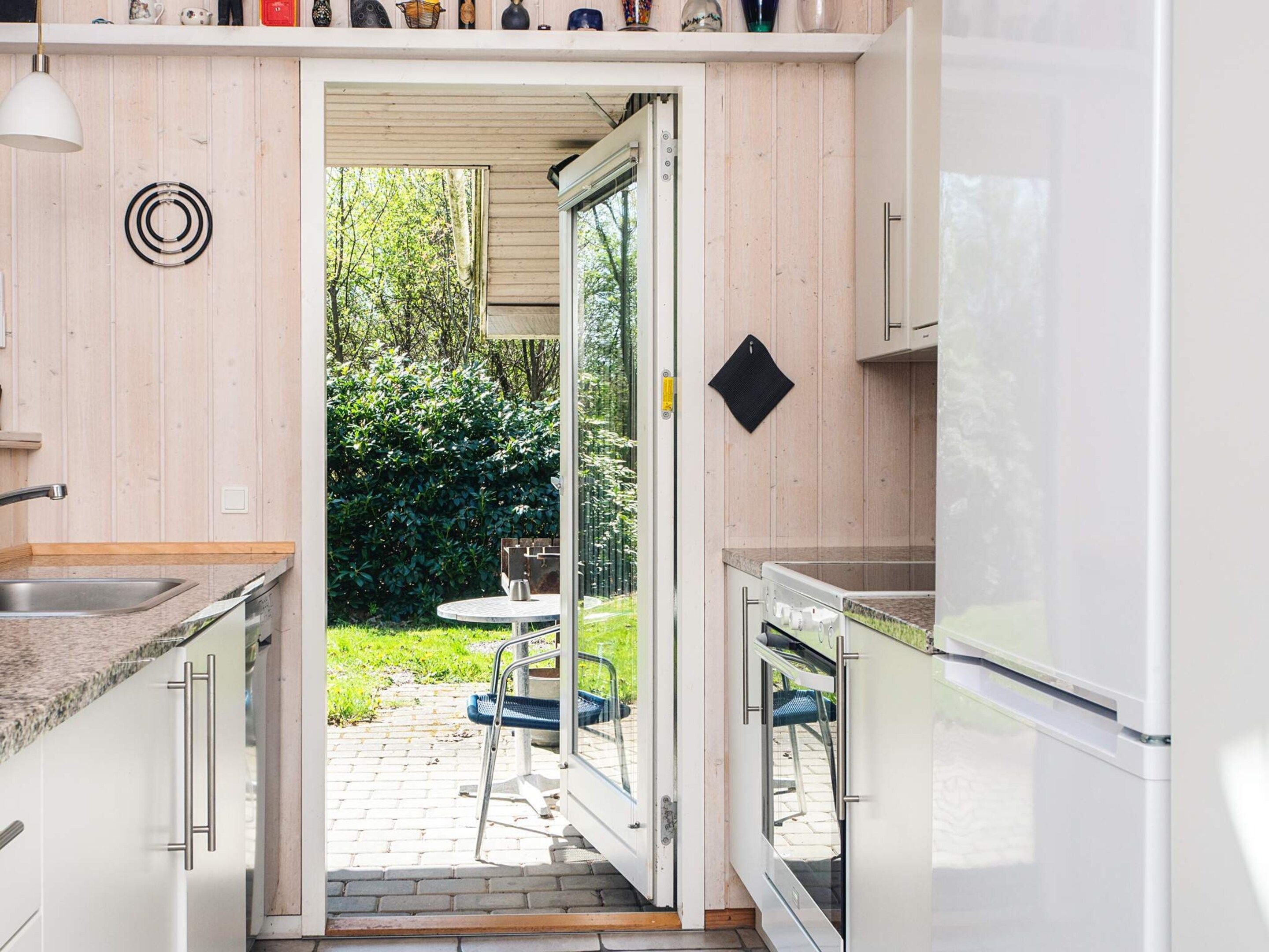 A modern kitchen with a sliding door leading to an outdoor area, a sink, and a refrigerator.