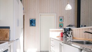 A modern kitchen with white cabinets, a granite countertop, a built-in oven, a coffee maker, and a sink. - 4 Star Holiday Home in Oksbol (Oksbol)
