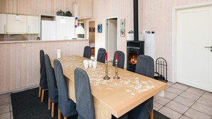 A modern interior with a long dining table, chairs, a kitchen area, and a fireplace. - 4 Star Holiday Home in Oksbol (Oksbol)