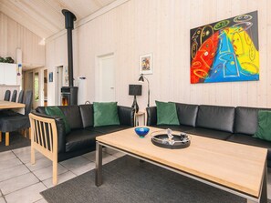 Un salon moderne avec un canapé en cuir noir, une table basse en bois et un tableau abstrait aux couleurs vives accroché au mur.