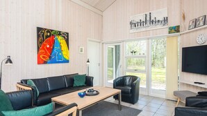 A modern living room with a black leather sofa, a wooden coffee table, and a colorful abstract painting. - 4 Star Holiday Home in Oksbol (Oksbol)