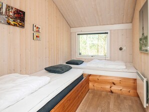 Eine Hütte mit zwei Betten, einem Fenster mit Blick auf Bäume und einer Holzvertäfelung.