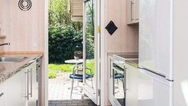 A modern kitchen with a sliding door leading to an outdoor area, a sink, and a refrigerator. - 4 Star Holiday Home in Oksbol (Oksbol)