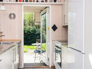 Et moderne køkken med en skydedør til et udendørs område, en vask og et køleskab.
