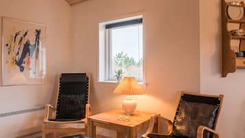 Una habitación con techo de madera, ventanal con vistas, una mesa con lámpara y dos sillas.