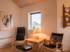 A room with a wooden ceiling, a window with a view, a table with a lamp, and two chairs. - 4 Star Holiday Home in Tarm (Tarm)