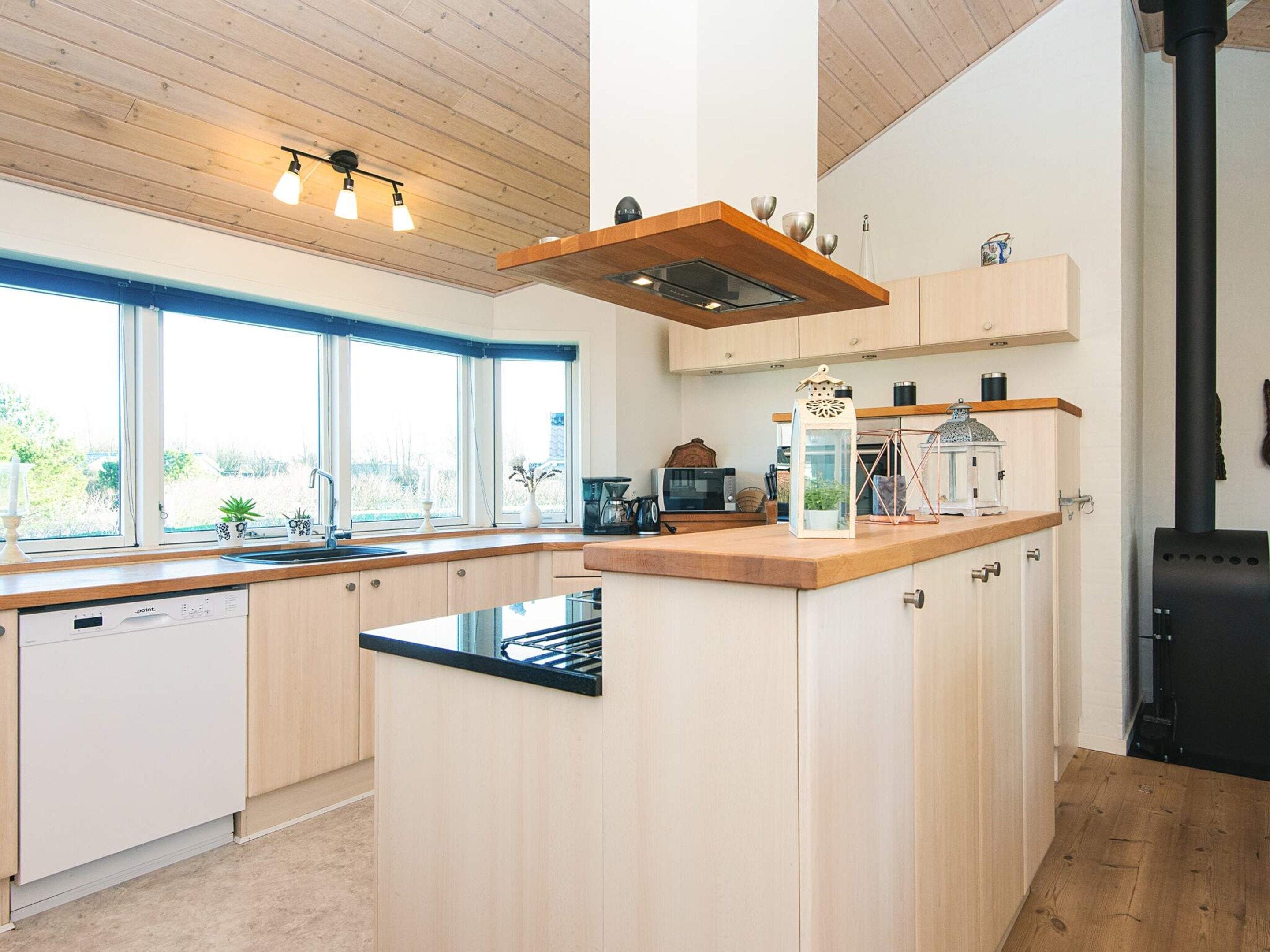 Una cocina moderna con una isla central, armarios de madera, microondas integrado y una estufa negra.