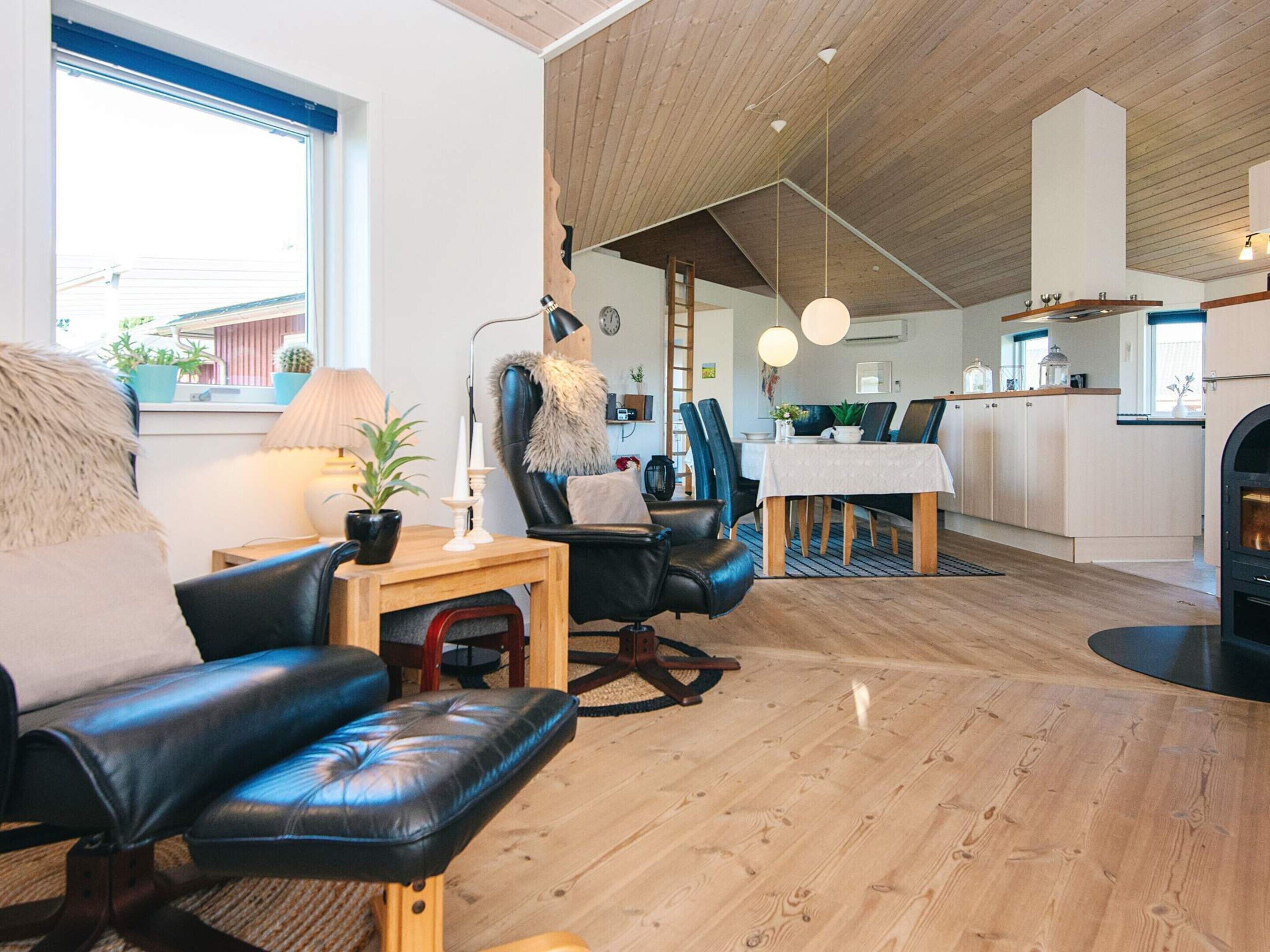 Uma sala de estar moderna com um sofá de couro, uma mesa de centro de madeira e uma área de jantar com mesa e cadeiras.