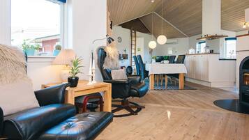 Uma sala de estar moderna com um sofá de couro, uma mesa de centro de madeira e uma área de jantar com mesa e cadeiras.