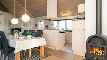 Una cocina moderna con una isla central, piso de madera y estufa de leña integrada.
