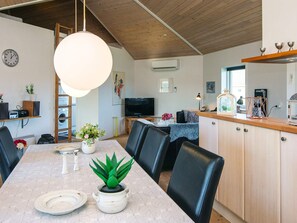 A modern kitchen with a dining table, chairs, and a hanging light fixture. - 4 Star Holiday Home in Tarm (Tarm)