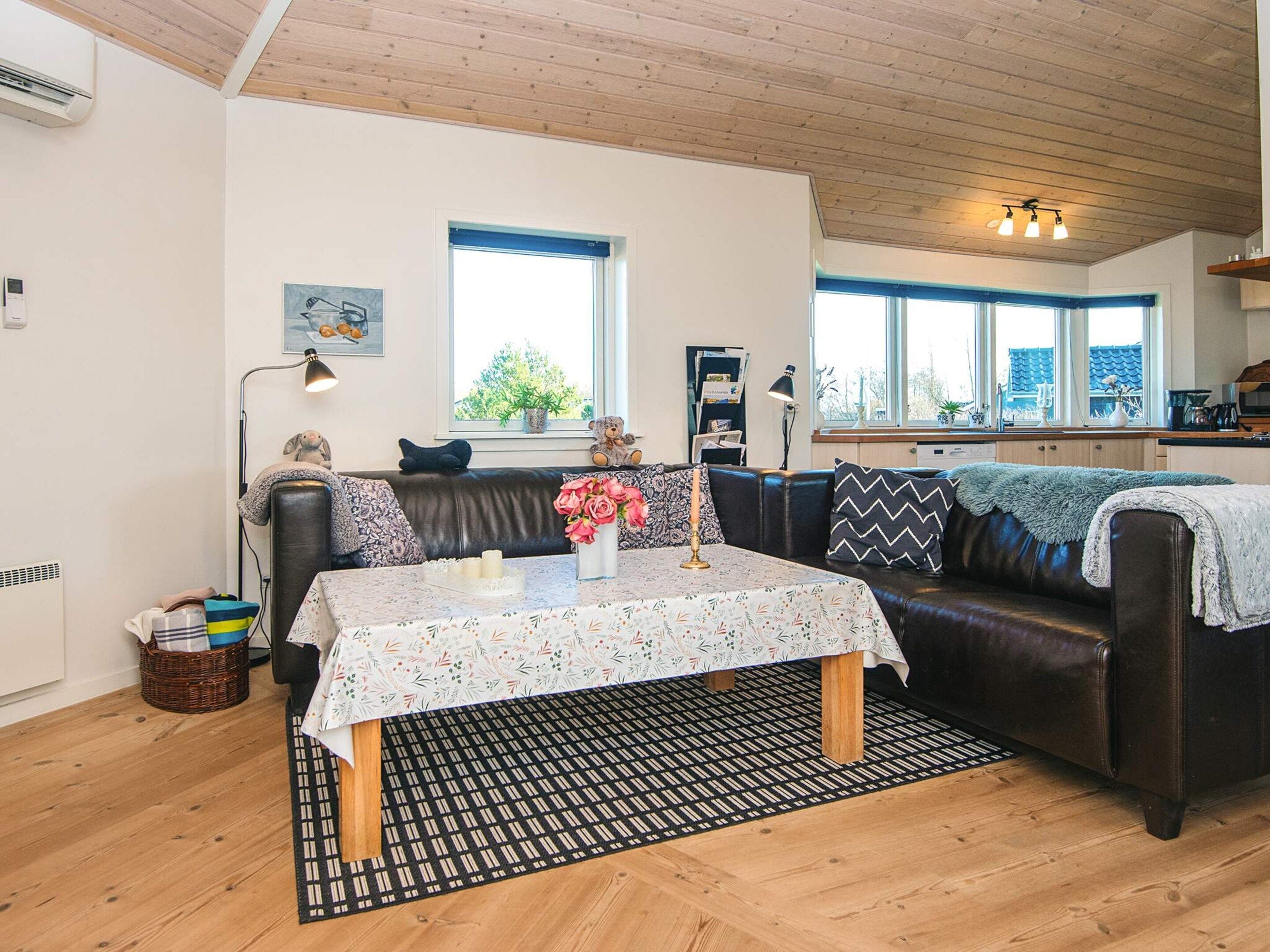 Una sala de estar acogedora con un sofá, una mesita de centro y vista a la cocina por una ventana.