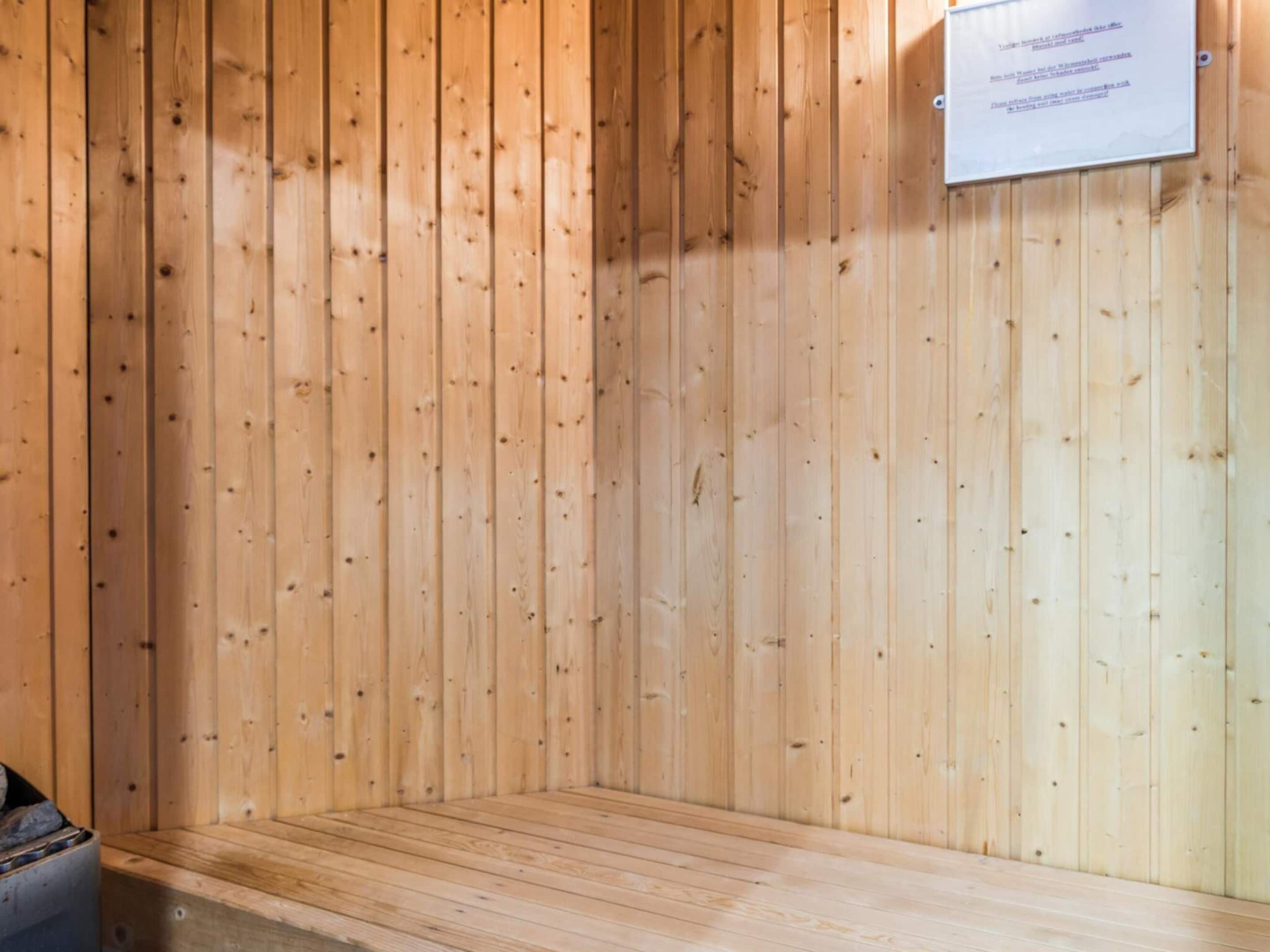A sauna room with wooden walls and a bench.