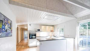 A modern kitchen with a large island, white cabinetry, and a view of the outdoors. - 4 Star Holiday Home in Blavand (Blavand)
