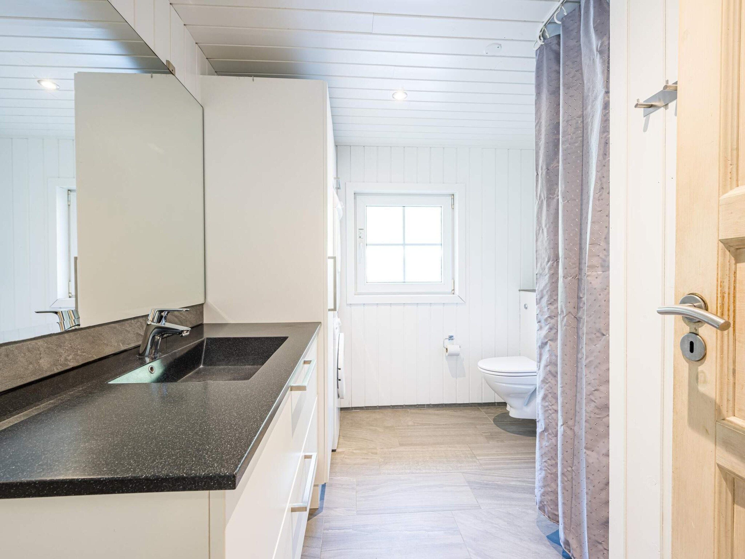 Une salle de bain moderne avec un grand miroir, un lavabo et des toilettes.