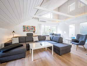 A modern living room with a sectional sofa, a white coffee table, and a grey armchair. - 4 Star Holiday Home in Blavand (Blavand)