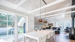 A modern kitchen with a large island, white cabinetry, and a black stove. - 4 Star Holiday Home in Blavand (Blavand)