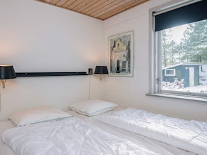 Ein Schlafzimmer mit zwei Betten, einem Fenster mit Blick auf eine verschneite Landschaft, einer Wandlampe und einem gerahmten Bild.