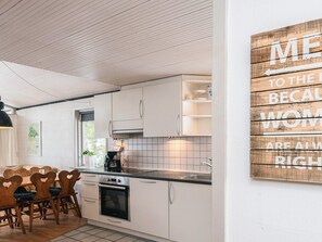 Eine moderne Küche mit weißen Schränken, einem eingebauten Backofen und einer Kaffeemaschine.