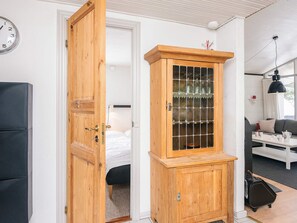 A room with a wooden cabinet, a bed, a sofa, and a clock on the wall. - 4 Person Holiday Home in Blavand (Blavand)