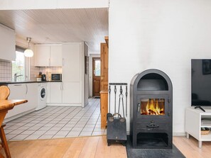 Eine moderne Küche mit eingebauter Waschmaschine, einem Holztisch und einem Kaminofen.