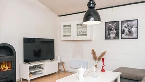 A modern living room with a fireplace, a flat-screen TV, a white coffee table, and a grey sofa.