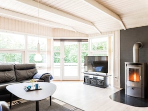 Un salon moderne comprenant un canapé, une table basse, un téléviseur et un poêle à bois.