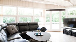 A modern living room with a leather sectional sofa, a round coffee table, and a flat-screen TV. - 5 Star Holiday Home in Hemmet (Hemmet)