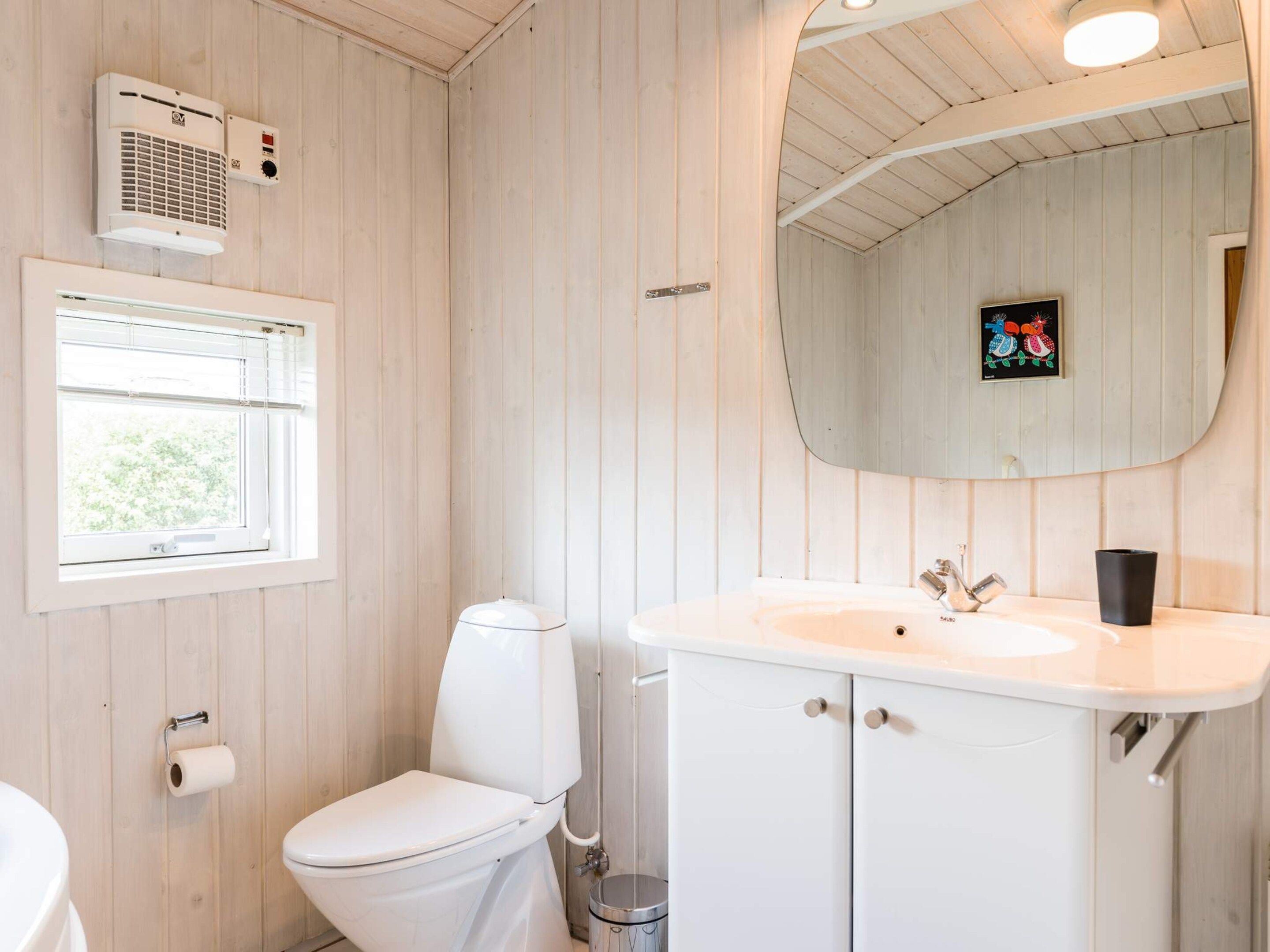 A bathroom with a toilet, sink, and window.