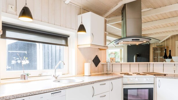 A modern kitchen with white cabinetry, a built-in dishwasher, a stove, and a microwave. - 5 Star Holiday Home in Hemmet (Hemmet)