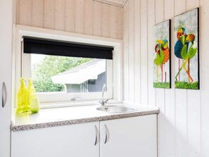 A kitchen with a window, a sink, and two yellow bottles on the counter.