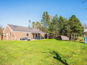 A brick house with a patio, a swing set, and a fenced yard. - 5 Star Holiday Home in Norre Nebel (Norre Nebel)