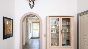 A hallway with a wooden cabinet, a framed picture, and a deer skull on the wall. - 5 Star Holiday Home in Norre Nebel (Norre Nebel)