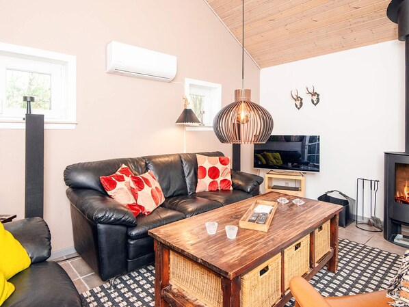 Una sala moderna con un sofá de cuero, una mesa de centro de madera, un televisor de pantalla plana y una chimenea.