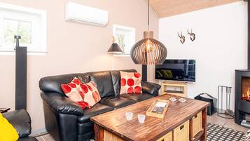 A modern living room with a leather sofa, a wooden coffee table, a TV, and a fireplace.