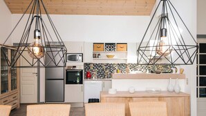 A modern kitchen with pendant lighting, a dining area with a wooden table, and a view of the living area. - 5 Star Holiday Home in Norre Nebel (Norre Nebel)