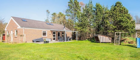 A brick house with a patio, a swing set, and a fenced yard.