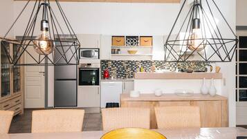 A modern kitchen with pendant lighting, a dining area with a wooden table, and a view of the living area.