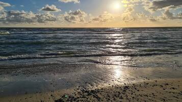 A beach with waves, a clear sky, and the sun.
